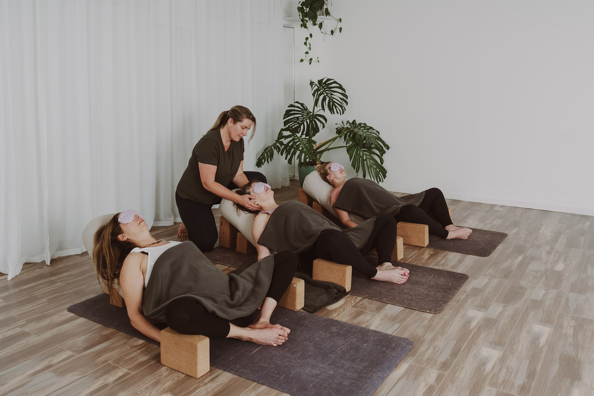 A restorative yoga class at the Joy studio, with students resting on bolsters